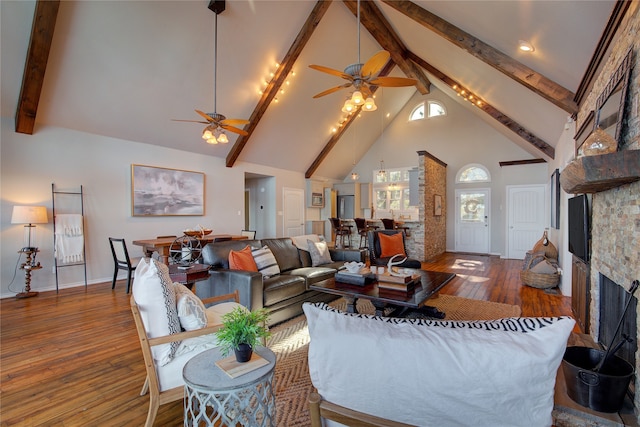 living room with hardwood / wood-style floors, high vaulted ceiling, ceiling fan, a fireplace, and beamed ceiling