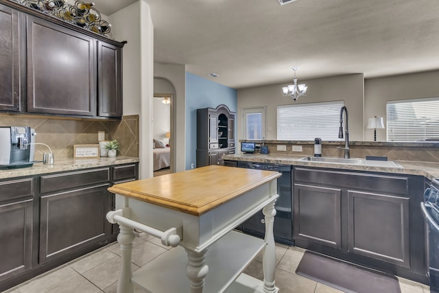 kitchen with dark brown cabinetry, sink, black dishwasher, tasteful backsplash, and light tile patterned floors