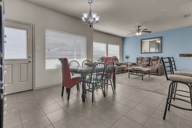 tiled dining area featuring ceiling fan with notable chandelier