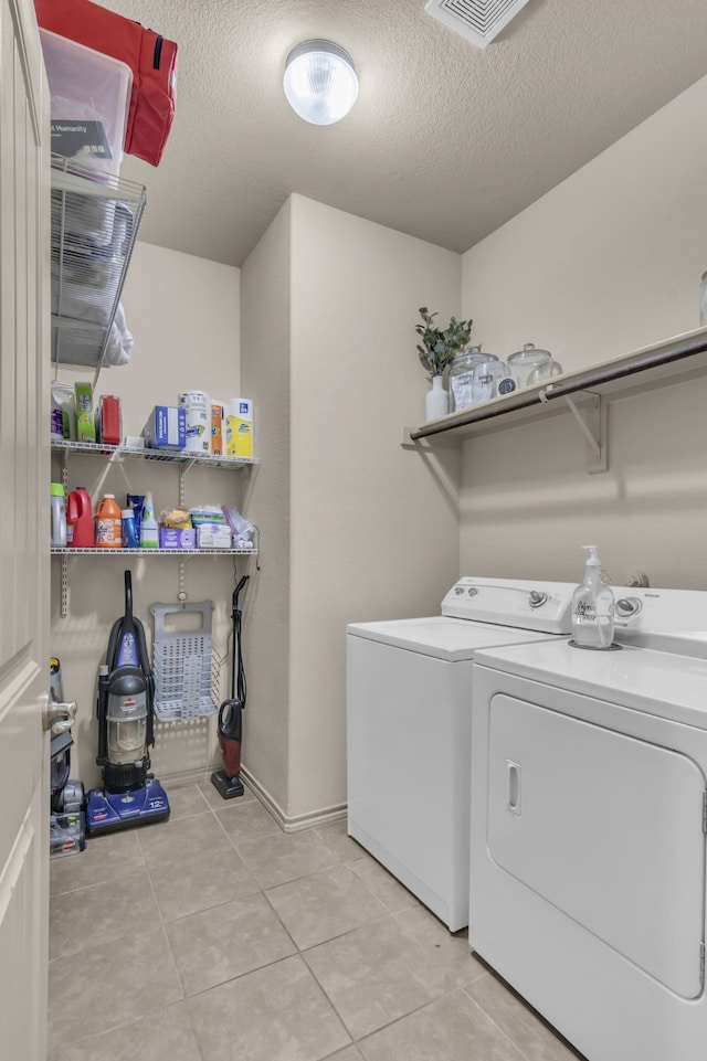 laundry room featuring separate washer and dryer, a textured ceiling, and light tile patterned floors