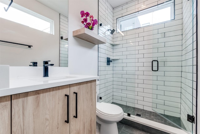 bathroom with tile patterned floors, vanity, toilet, and a shower with shower door