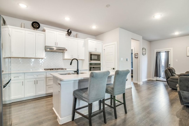 kitchen featuring appliances with stainless steel finishes, sink, a breakfast bar area, white cabinets, and a center island with sink