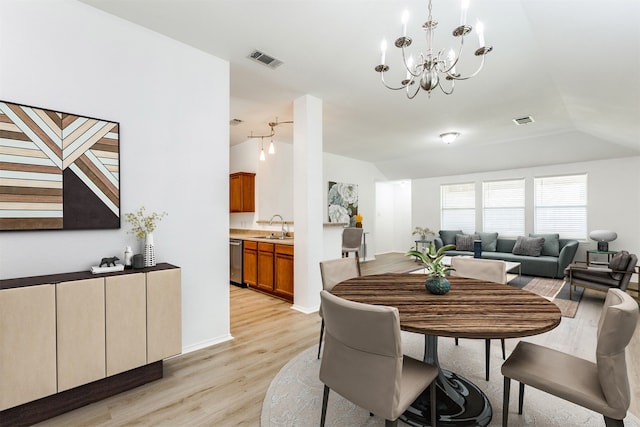 dining space with lofted ceiling, sink, an inviting chandelier, and light hardwood / wood-style floors