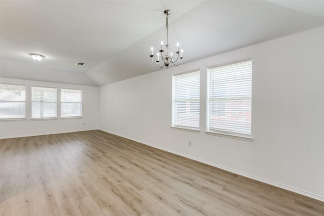 empty room featuring vaulted ceiling, an inviting chandelier, and light hardwood / wood-style flooring