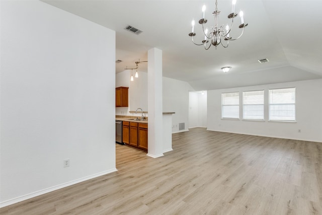 unfurnished living room featuring vaulted ceiling, an inviting chandelier, light hardwood / wood-style floors, and sink