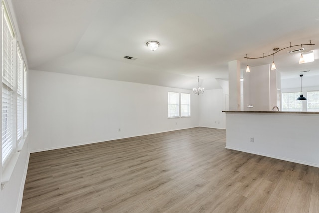 unfurnished living room with a chandelier, lofted ceiling, and wood-type flooring