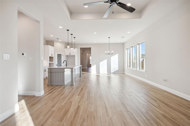 unfurnished living room with ceiling fan with notable chandelier and sink