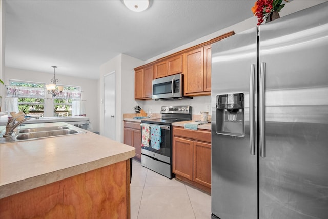 kitchen featuring appliances with stainless steel finishes, sink, light tile patterned floors, a chandelier, and hanging light fixtures