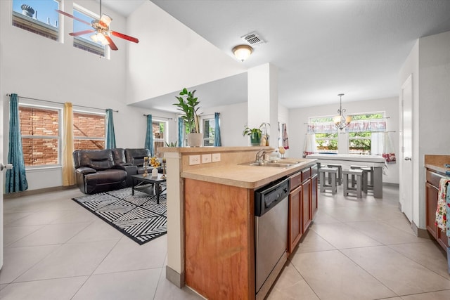 kitchen featuring dishwasher, pendant lighting, a kitchen island with sink, light tile patterned floors, and ceiling fan with notable chandelier