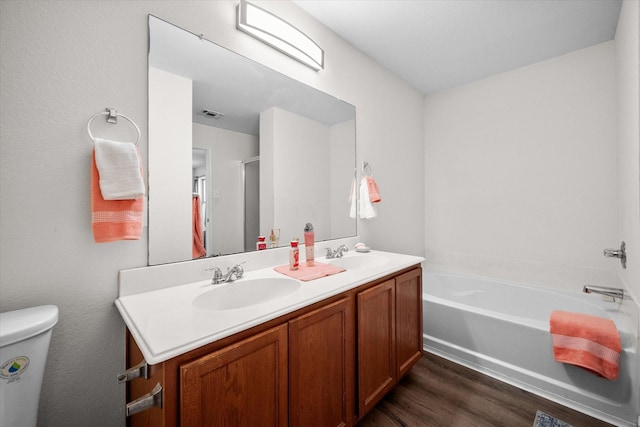 bathroom featuring hardwood / wood-style floors, vanity, toilet, and a tub