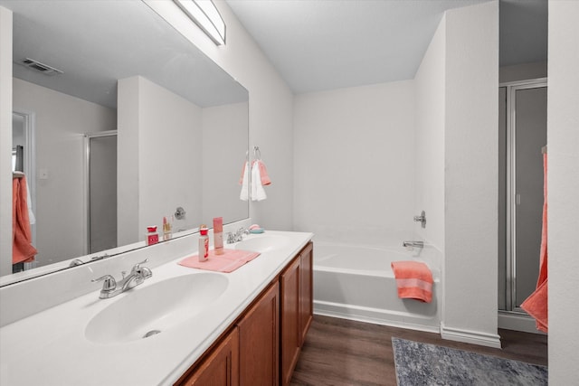 bathroom with hardwood / wood-style floors, vanity, and shower with separate bathtub