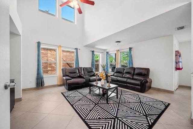 tiled living room with ceiling fan and a high ceiling