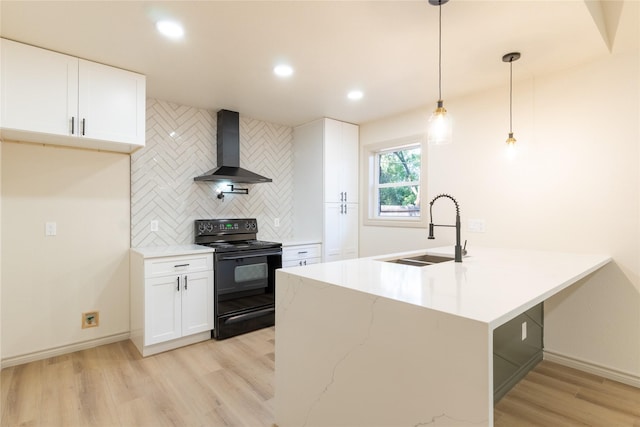 kitchen with black / electric stove, sink, wall chimney range hood, white cabinetry, and hanging light fixtures