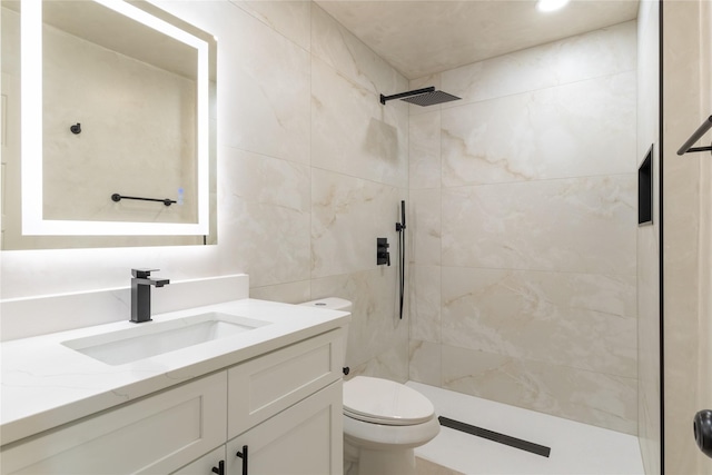 bathroom featuring a tile shower, vanity, and toilet