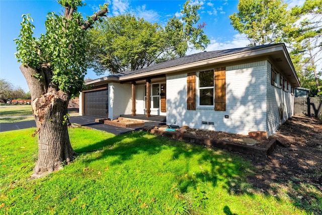 single story home with covered porch, a garage, and a front yard