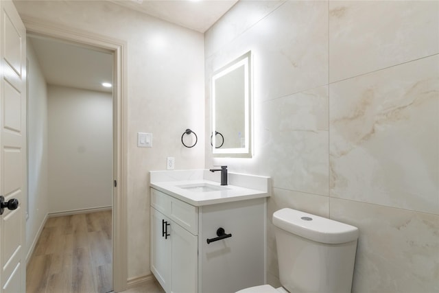 bathroom featuring hardwood / wood-style floors, vanity, tile walls, and toilet