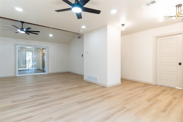 empty room featuring ceiling fan with notable chandelier, light hardwood / wood-style flooring, and lofted ceiling