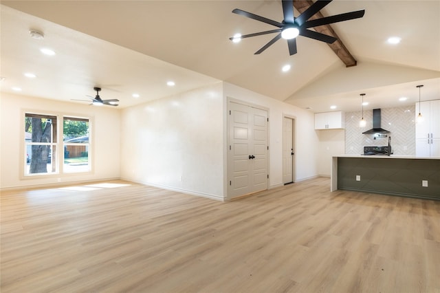 unfurnished living room with ceiling fan, lofted ceiling with beams, and light wood-type flooring