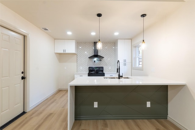 kitchen with white cabinetry, sink, wall chimney range hood, black / electric stove, and decorative light fixtures