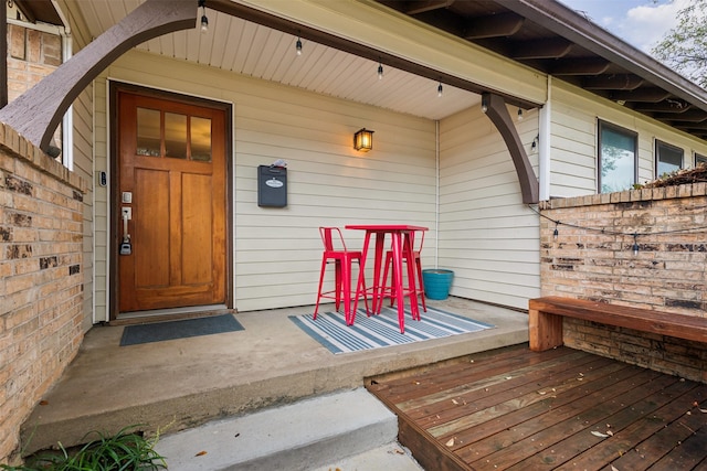 view of exterior entry featuring covered porch and brick siding