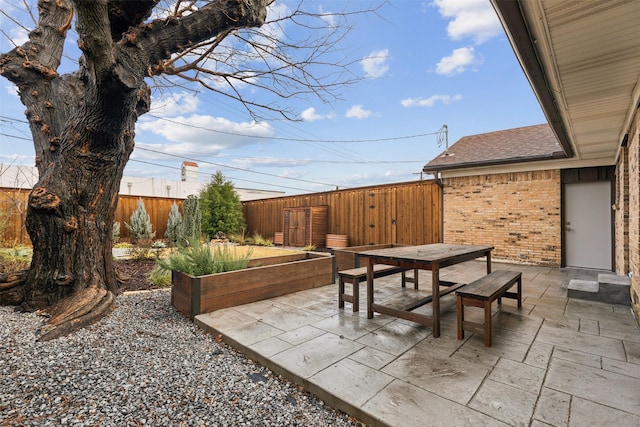 view of patio featuring outdoor dining space, a garden, and fence