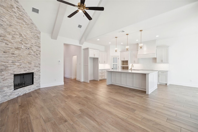 unfurnished living room featuring high vaulted ceiling, sink, ceiling fan, a fireplace, and beamed ceiling