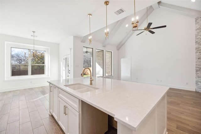 kitchen with a center island with sink, plenty of natural light, white cabinets, and sink