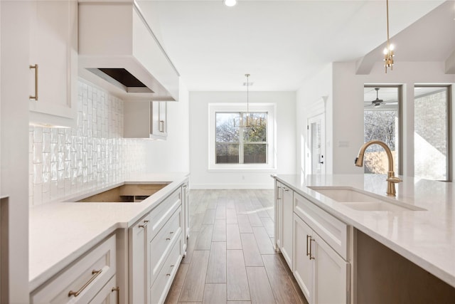 kitchen with pendant lighting, backsplash, custom exhaust hood, and sink