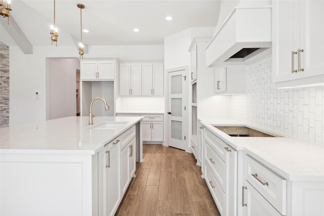 kitchen featuring premium range hood, white cabinetry, light stone countertops, and hanging light fixtures