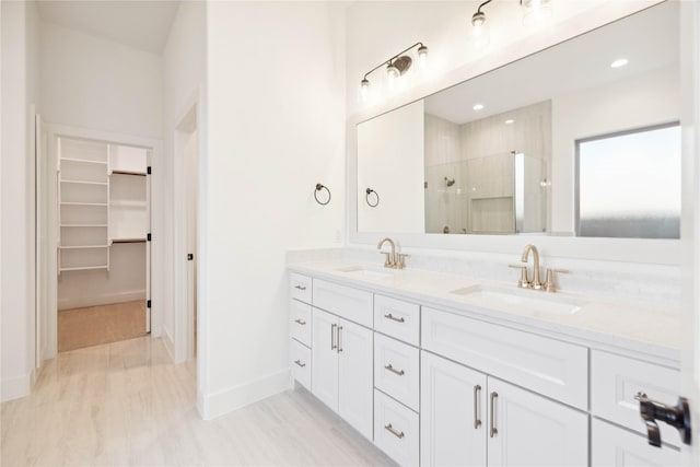 bathroom featuring a shower with door and vanity