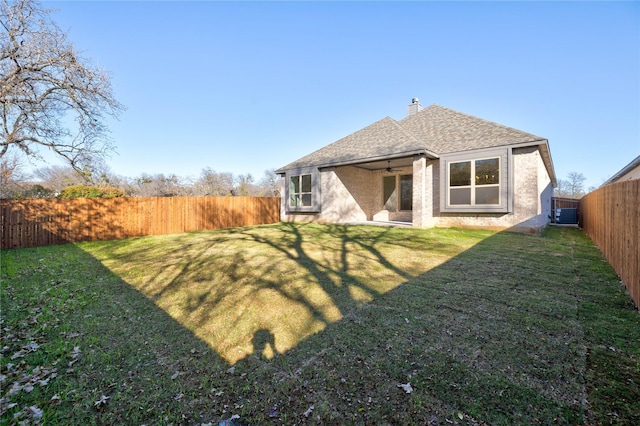 rear view of property featuring a lawn and ceiling fan