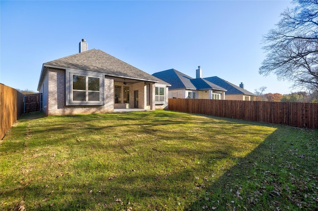 back of house with ceiling fan and a yard