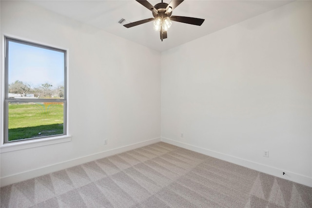 empty room featuring ceiling fan, light colored carpet, and a wealth of natural light