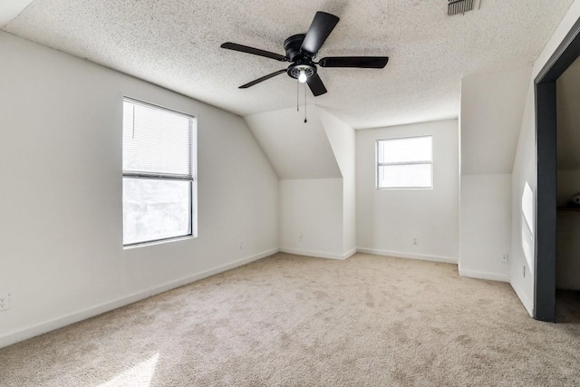 bonus room with vaulted ceiling, light colored carpet, a textured ceiling, and ceiling fan