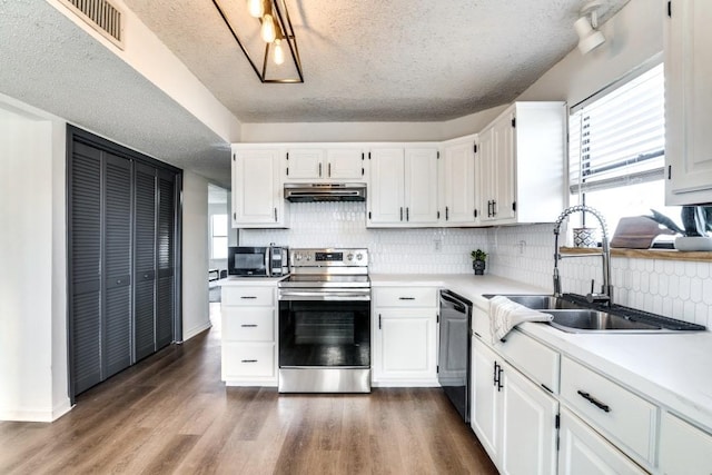 kitchen featuring dark wood-type flooring, sink, white cabinetry, stainless steel appliances, and decorative backsplash