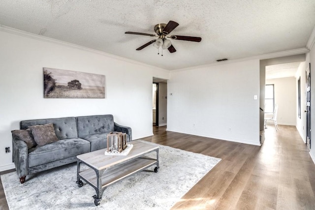 living room with ceiling fan, wood-type flooring, ornamental molding, and a textured ceiling