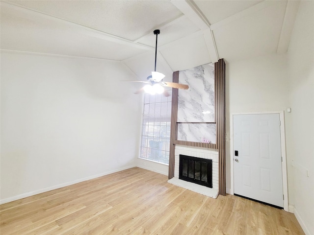 unfurnished living room with light wood finished floors, baseboards, a ceiling fan, lofted ceiling, and a brick fireplace