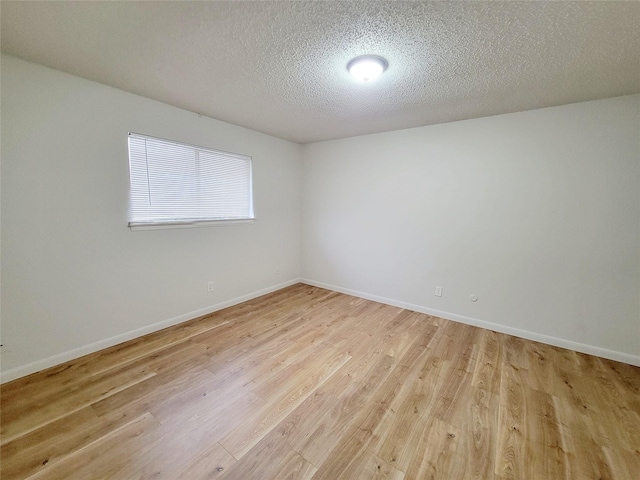 spare room with a textured ceiling and light wood-type flooring