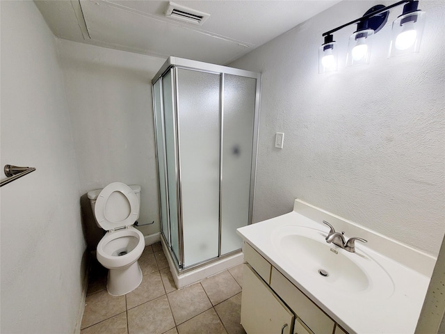 bathroom featuring tile patterned flooring, vanity, toilet, and walk in shower