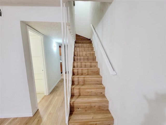 stairway featuring hardwood / wood-style floors and a textured ceiling