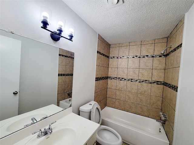 full bathroom featuring a textured ceiling, vanity, tiled shower / bath combo, and toilet