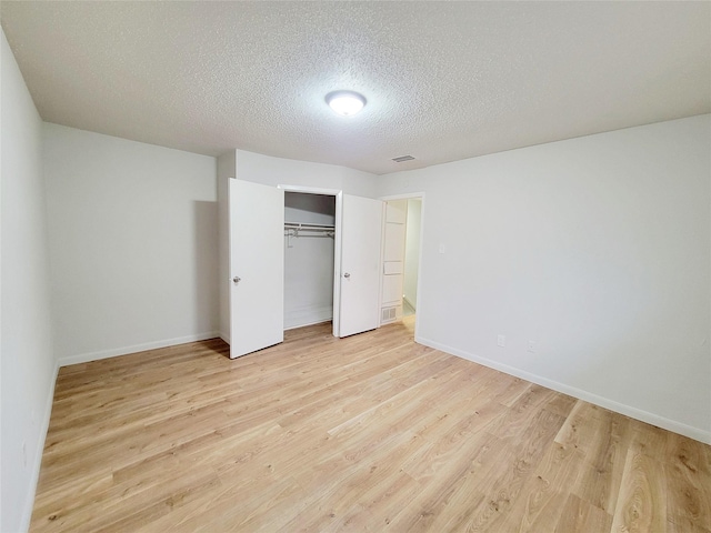 unfurnished bedroom featuring a textured ceiling, light hardwood / wood-style floors, and a closet