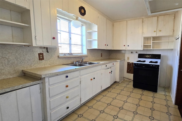 kitchen featuring white cabinets, black range with gas stovetop, backsplash, and sink