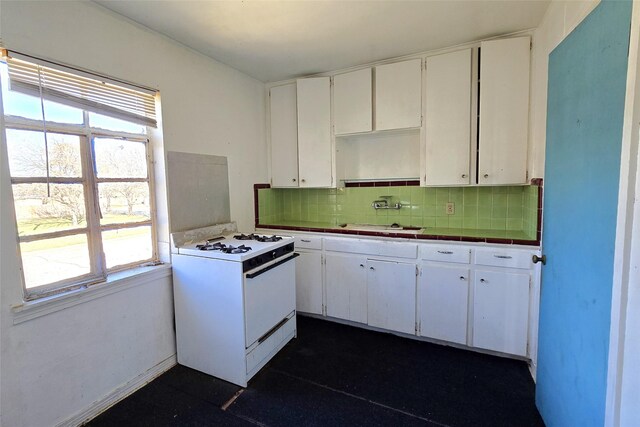 kitchen featuring white cabinets, white range with gas stovetop, sink, and tasteful backsplash