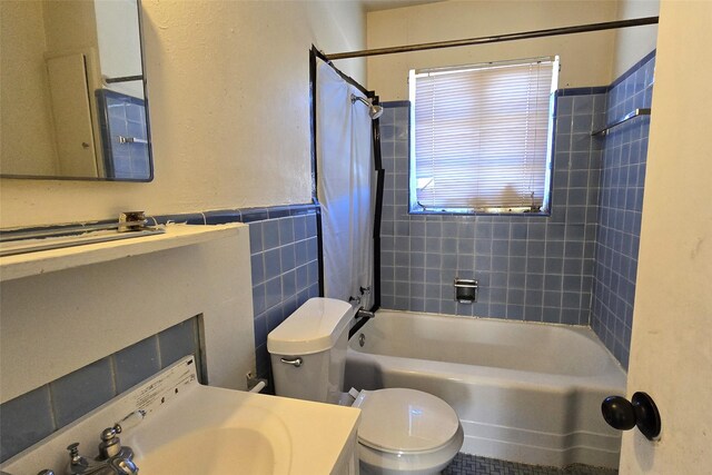 full bathroom with toilet, vanity, tile walls, and tiled shower / bath