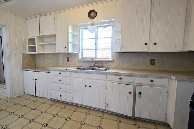 kitchen with decorative backsplash, white cabinetry, sink, and hanging light fixtures