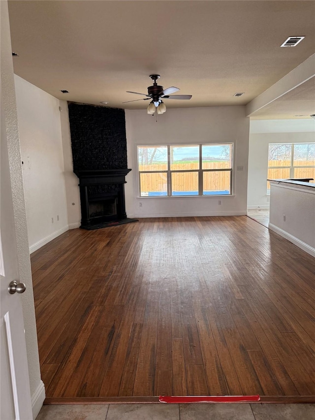 unfurnished living room featuring plenty of natural light, a fireplace, visible vents, and wood finished floors