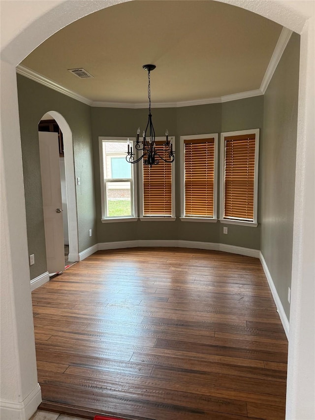 unfurnished dining area with hardwood / wood-style flooring, an inviting chandelier, and ornamental molding