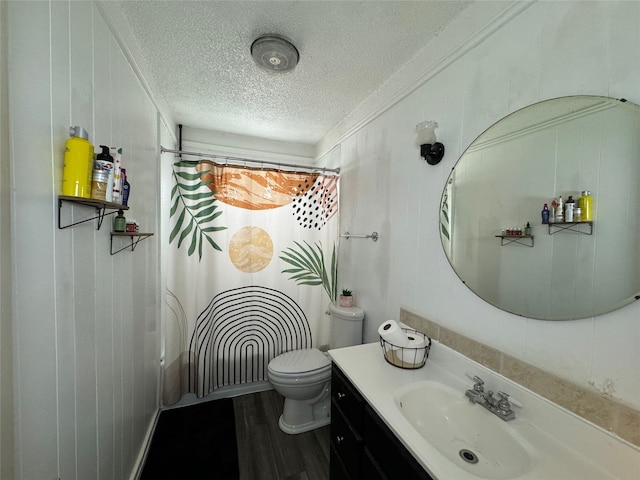 bathroom with hardwood / wood-style floors, wood walls, vanity, toilet, and a textured ceiling