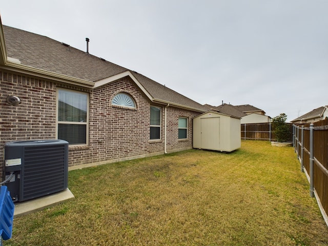 back of house featuring central air condition unit, a yard, and a storage unit